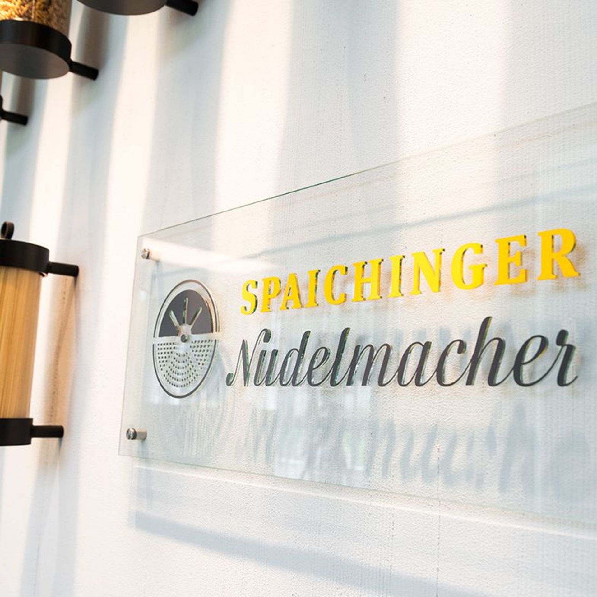 The logo of the Spaichinger Nudelmacher is written on a glass sign attached to a white wall